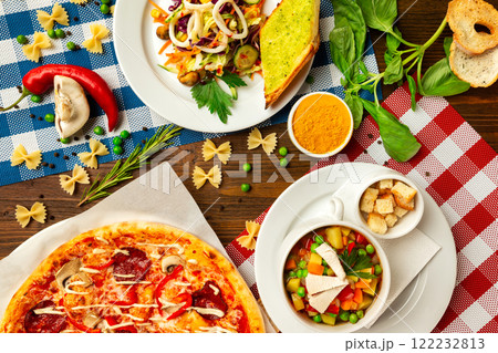 Top view image of italian style business lunch of pizza, soup and salad at wooden table background. Top view image of italian style business lunch of pizza, soup and salad at wooden table background. 122232813