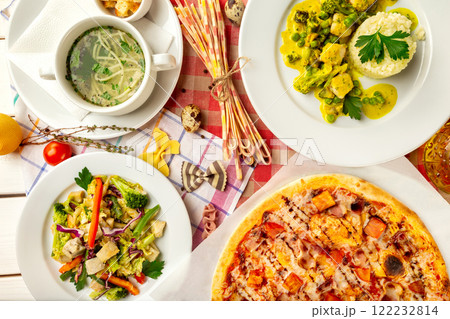 Top view image of italian style business lunch of pizza, soup, steamed vegetables and salad at wooden table background. Top view image of italian style business lunch of pizza, soup, steamed vegetables and salad at wooden table background. 122232814