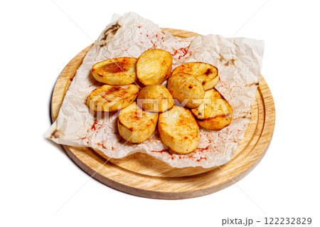 Fried potato wedges on a wooden tray board with paper isolated at white background. Fried potato wedges on a wooden tray board with paper isolated at white background. 122232829