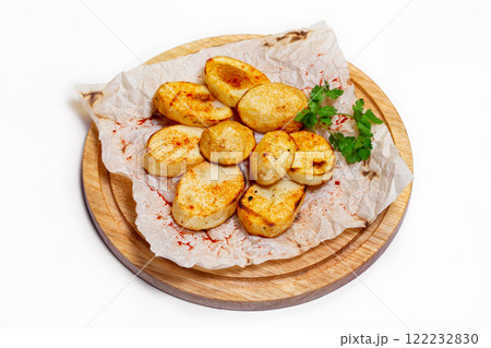 Fried potato wedges on a wooden tray board with paper isolated at white background. Fried potato wedges on a wooden tray board with paper isolated at white background. 122232830