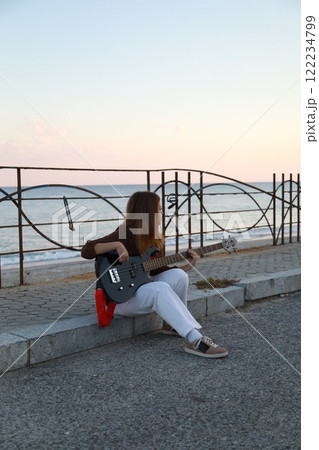 Girl Plays The Bass Instrument Sitting On The Step Near The Street At Evening 122234799