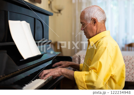 Old man playing piano at home 122234948