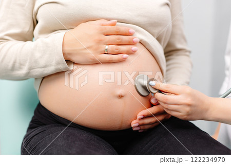 Female doctor using stethoscope examining pregnant woman in clinic. Medical exam pregnant woman Female doctor using stethoscope examining pregnant woman in clinic. Medical exam pregnant woman 122234970