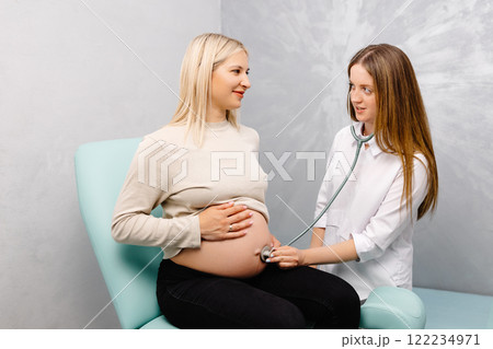 Female doctor using stethoscope examining pregnant woman in clinic. Medical exam pregnant woman Female doctor using stethoscope examining pregnant woman in clinic. Medical exam pregnant woman 122234971