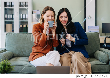 Female colleague caucasian descent holds a cup of coffee and talking discussion ideas and happily. Female colleague caucasian descent holds a cup of coffee and talking discussion ideas and happily. 122235474