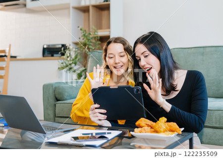 Happy two woman having fun doing video call using mobile phone sitting on sofa. Happy two woman having fun doing video call using mobile phone sitting on sofa. 122235509