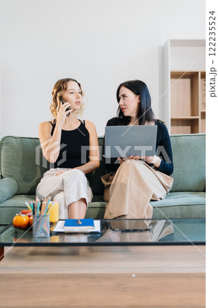 Office Lifestyle: Two Woman Reviews Business Project at Home Office. Office Lifestyle: Two Woman Reviews Business Project at Home Office. 122235524