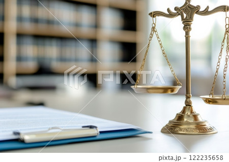 A golden balance scale stands on a desk in a well-lit office, symbolizing justice and law A golden balance scale stands on a desk in a well-lit office, symbolizing justice and law 122235658