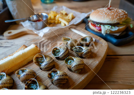 Delicious escargot and cheeseburger with fries on wooden table 122236323