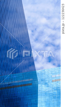Urban Reflection. Strikingly sharp angles of a glass skyscraper reflecting the dynamic patterns of clouds, illustrating the harmony between modern architecture and nature 122236423