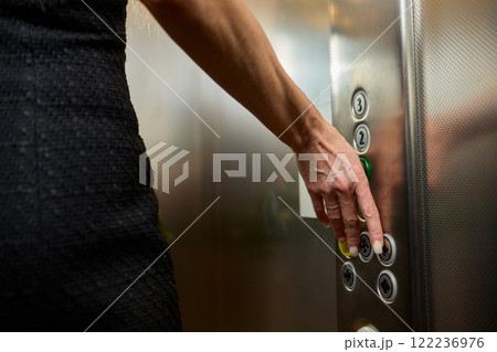Pressing the elevator button in contemporary high rise buildings signifies modern urban convenience 122236976