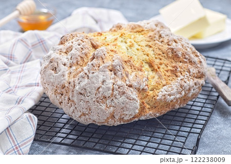 Freshly baked soda bread on cooling rack with butter and honey in the background, horizontal Freshly baked soda bread on cooling rack with butter and honey in the background, horizontal 122238009