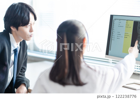 腰のレントゲンを見ながら問診をするミドルの女性医師と患者 腰のレントゲンを見ながら問診をするミドルの女性医師と患者 122238776
