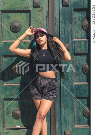 Young woman leaning against a large old Green door. 122239153