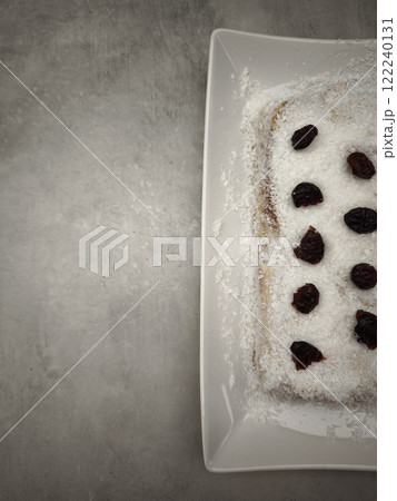 Delicious christmas pudding decorated with coconut flakes and cherries on modern plate party food for aperitif, New Year's Eve dinner, Christmas or birthday 122240131