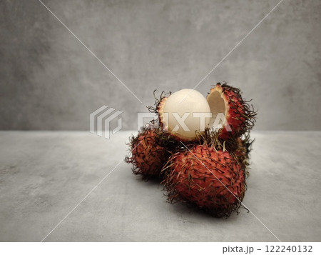 Fresh rambutan fruit showing white flesh on grey table 122240132