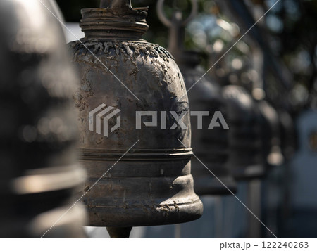Traditional antique bells hang in an outdoor temple in Thailand. Close-up of beautiful bells lined up in a Buddhist temple or place in Thailand. Calm and believe. 122240263