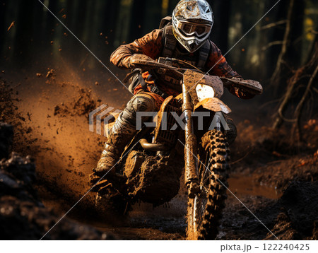 A dirt bike motorcycle is being ridden on a muddy off road. 122240425