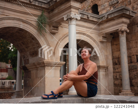 Woman walking narrow streets of old town Antalya during warm summer evening. Historic atmosphere and Mediterranean charm creates peaceful travel experience. at Hadrian's Gate in Antalya Turkey. 122241048