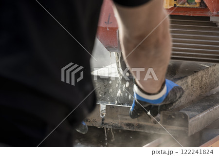 Rear view of a person using a circular saw or angle grinder 122241824