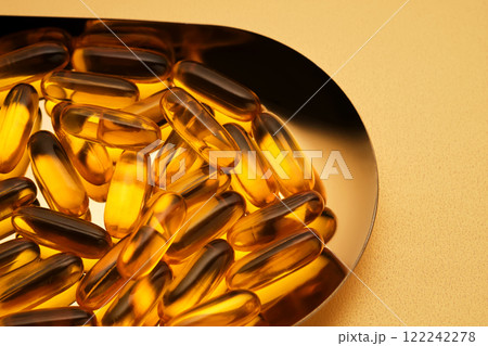 Yellow capsules with Omega-3 fish oil on a golden tray. 122242278