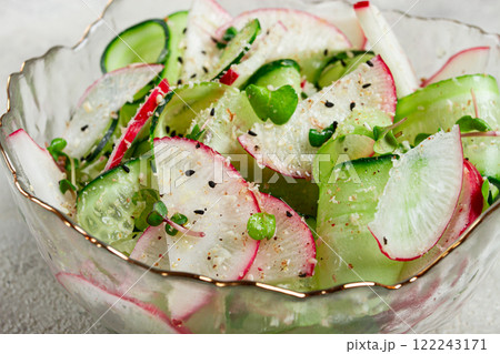Fresh salad with cucumbers and radishes served in a decorative bowl during a sunny afternoon gathering Fresh salad with cucumbers and radishes served in a decorative bowl during a sunny afternoon gathering 122243171