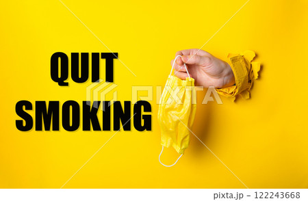 Person holding a yellow surgical mask with the words quit smoking Person holding a yellow surgical mask with the words quit smoking 122243668