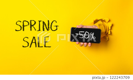 Person holding a cell phone with the words Spring Sale written on it 122243709