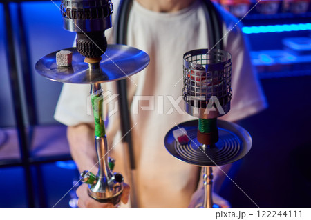 Close up of a hookah made of metal and glass on a wooden table 122244111