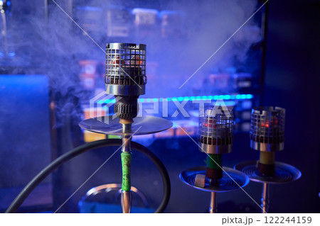 Close up of a hookah made of metal and glass on a wooden table Close up of a hookah made of metal and glass on a wooden table 122244159