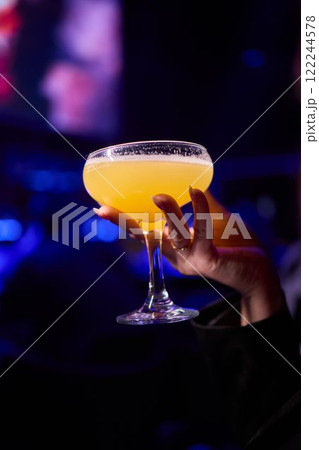 Elegant and Stunning Cocktail Glasses Clinking Together in a Softly Dimly Lit Bar Setting 122244578