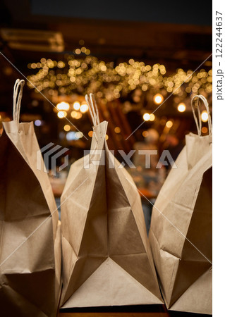 There are three craft paper bags placed neatly on a rustic wooden counter inside a cafe setting 122244637