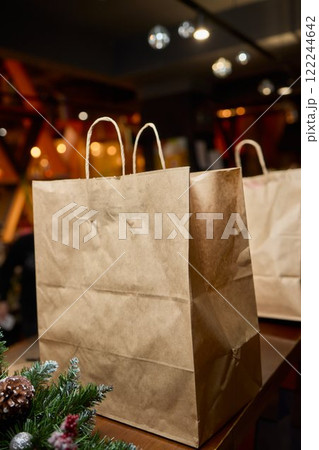 There are three craft paper bags placed neatly on a rustic wooden counter inside a cafe setting There are three craft paper bags placed neatly on a rustic wooden counter inside a cafe setting 122244642