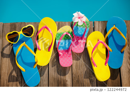 Beach flip-flops and sunglasses on wooden planks near swimming pool 122244972