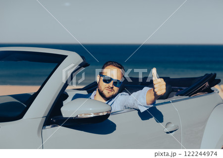 Successful young businessman on a beach. Man sitting in the cabriolet classic car. Successful young businessman on a beach. Man sitting in the cabriolet classic car. 122244974