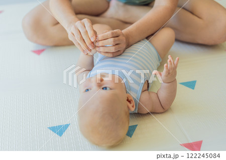 A mother gently massages her baby tiny fingers and palms, promoting relaxation and stimulation. A tender bonding moment focused on care, love, and early development. Baby care, touch therapy, and 122245084