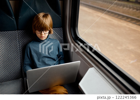 Child Focused on Laptop by Train Window. 122245366