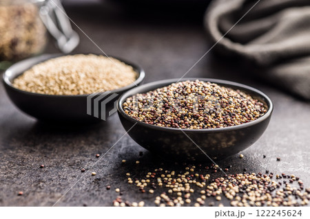 Mixed uncooked quinoa seeds in bowl on black table. 122245624