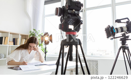 Script sign. Vlog studio. Woman writing near professional cameras spotlights. Media recording project work technical task. Script sign. Vlog studio. Woman writing near professional cameras spotlights. Media recording project work technical task. 122246629