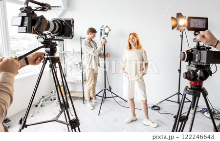 Behind scene. Female posing. Team work on preparing studio equipment work. Video operator photographer model lighting set up shooting. Behind scene. Female posing. Team work on preparing studio equipment work. Video operator photographer model lighting set up shooting. 122246648