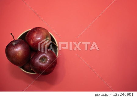 ripe red apples in a large paper cup on a red background 122246901