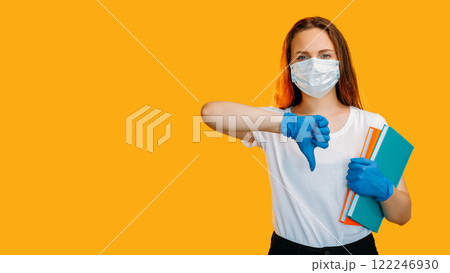 Quarantine dislike. Pandemic protest. COVID-19 lockdown remote education. Skeptic woman in protective face mask gloves showing no with thumb down gesture isolated on copy space. Quarantine dislike. Pandemic protest. COVID-19 lockdown remote education. Skeptic woman in protective face mask gloves showing no with thumb down gesture isolated on copy space. 122246930