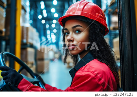 Electric reach truck driven by young black woman. Electric reach truck driven by young black woman. 122247123