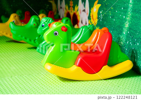 Bright plastic rocking horses in a cheerful indoor play area for kids. Bright plastic rocking horses in a cheerful indoor play area for kids. 122248121