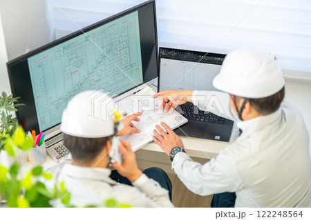 工事工程表を説明する男性主任技術者 ネットワーク工程表 工事監理 ヘルメット 2人 工事工程表を説明する男性主任技術者 ネットワーク工程表 工事監理 ヘルメット 2人 122248564