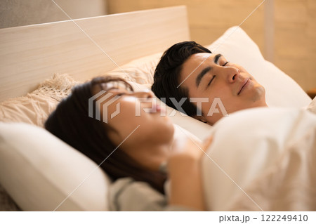 間接照明の部屋で寝る目を閉じるカップル　睡眠や熟睡などのイメージ 122249410
