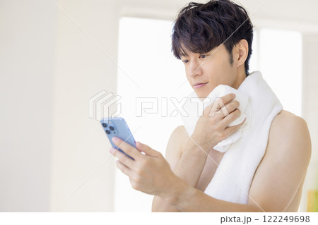 ビューティーイメージ お風呂上がりにスマホを見る男性 ビューティーイメージ お風呂上がりにスマホを見る男性 122249698