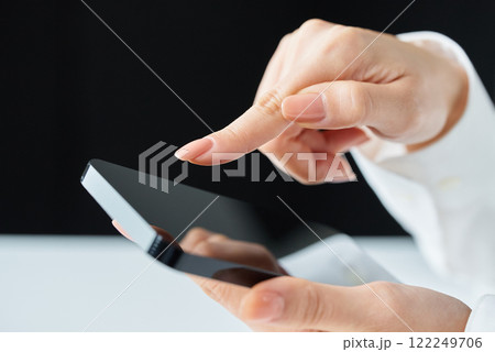スマートフォンの画面をタッチ操作する手元 122249706