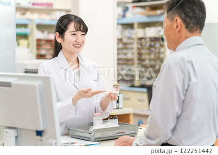 薬局のレジで薬の説明をする薬剤師の女性と高齢者男性 薬局のレジで薬の説明をする薬剤師の女性と高齢者男性 122251447