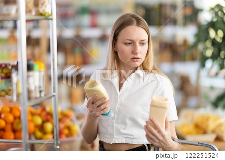 Young woman choosing mayonnaise in grocery store Young woman choosing mayonnaise in grocery store 122251524